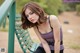 A woman sitting on a green bench in a park.