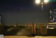 A woman standing on a bridge looking at the city at night.