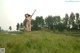 A naked woman jumping in the air in a field.