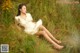 A woman in a white dress sitting in tall grass.