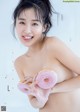 A naked woman holding a pink donut in her hands.