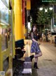 A woman in a dress and boots standing on a sidewalk.