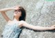 A woman leaning against a rock with her arms outstretched.