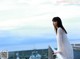 A woman in a white sweater standing on a railing.