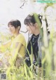 A couple of women sitting next to each other in a field.