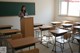 A woman standing at a podium in front of a blackboard.