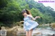 A woman in a blue and white dress standing in a river.