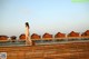 A woman in a white dress standing on a wooden bridge.