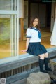 A woman in a school uniform sitting on a bench.