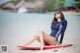 A woman sitting on a surfboard on the beach.