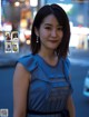 A woman in a blue dress standing on a city street.