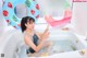A woman sitting in a bathtub with two inflatable watermelon rings.