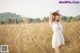 A woman in a white dress standing in a field.