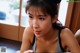 A woman in a gray tank top sitting at a table.